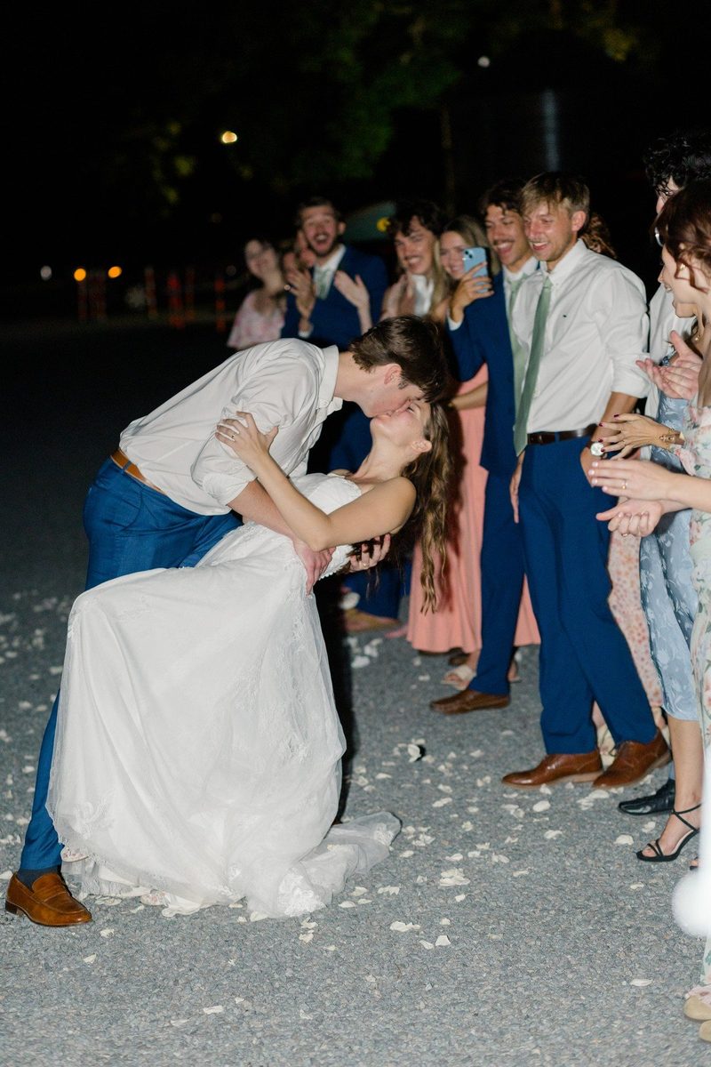 Groom dips the bride during a petal send-off at night