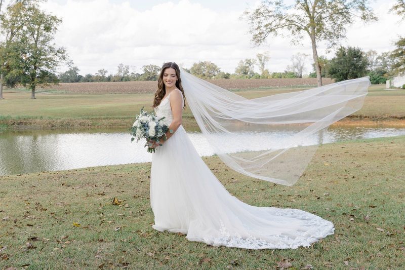 Bride's veil trails across a lakeside lawn