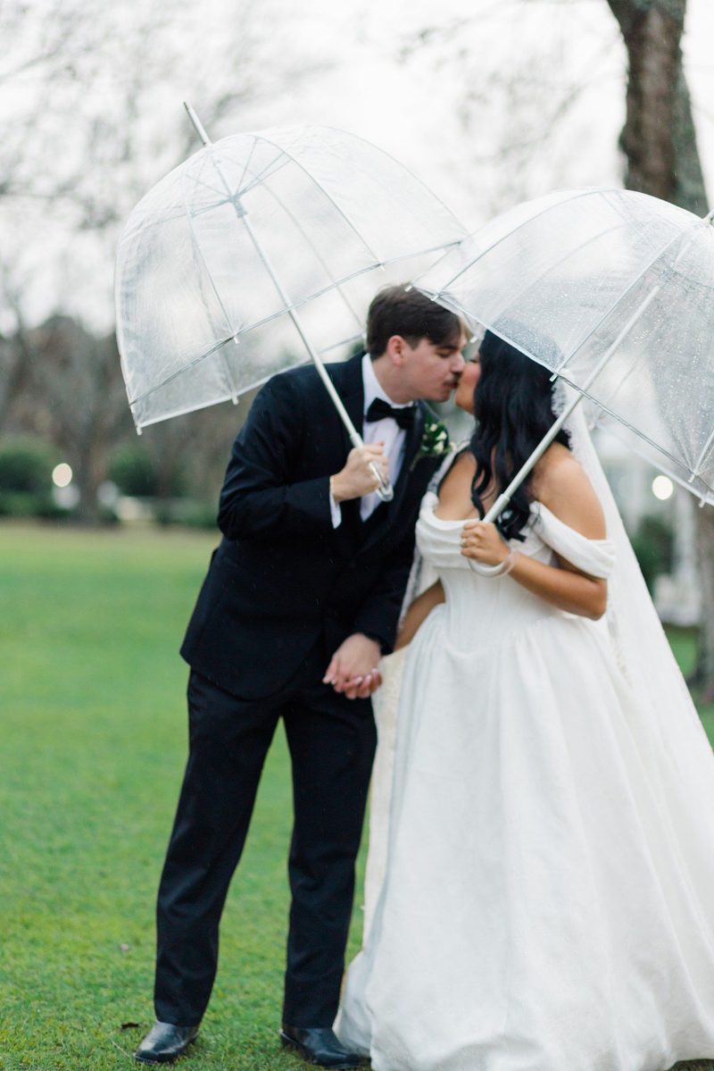 Couple kiss beneath clear umbrellas in the rain
