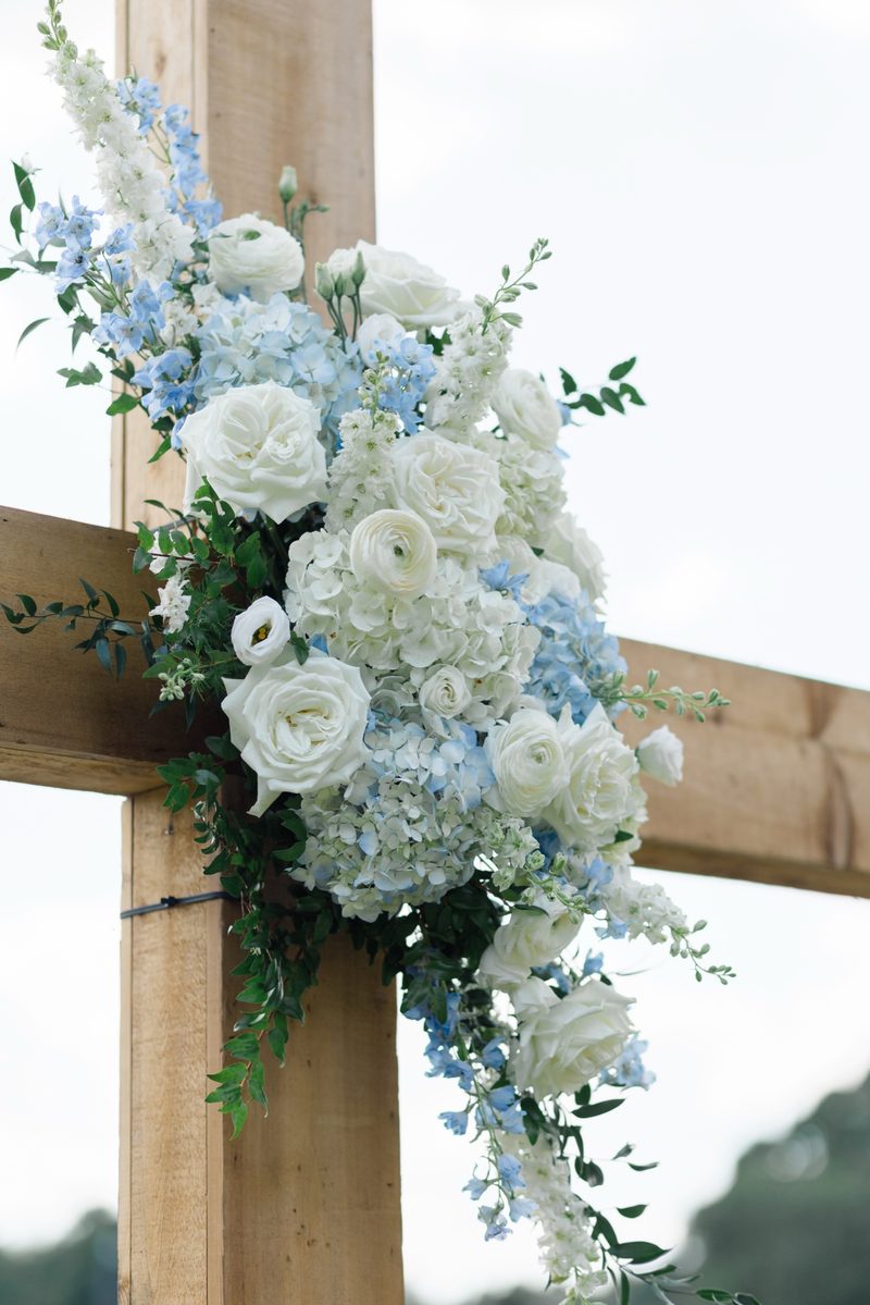 Blue and white florals draped on a wooden ceremony cross