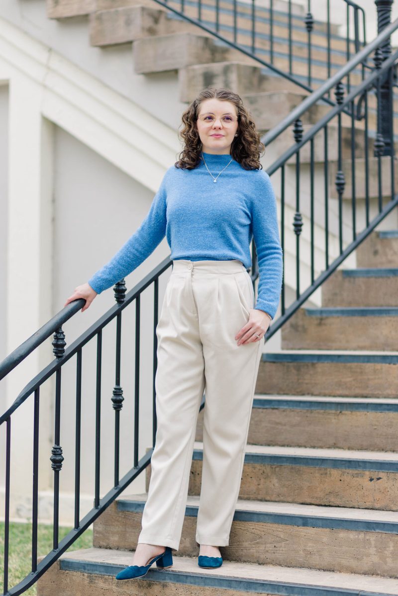 Morgan stands on a stone staircase with an iron railing, smiling