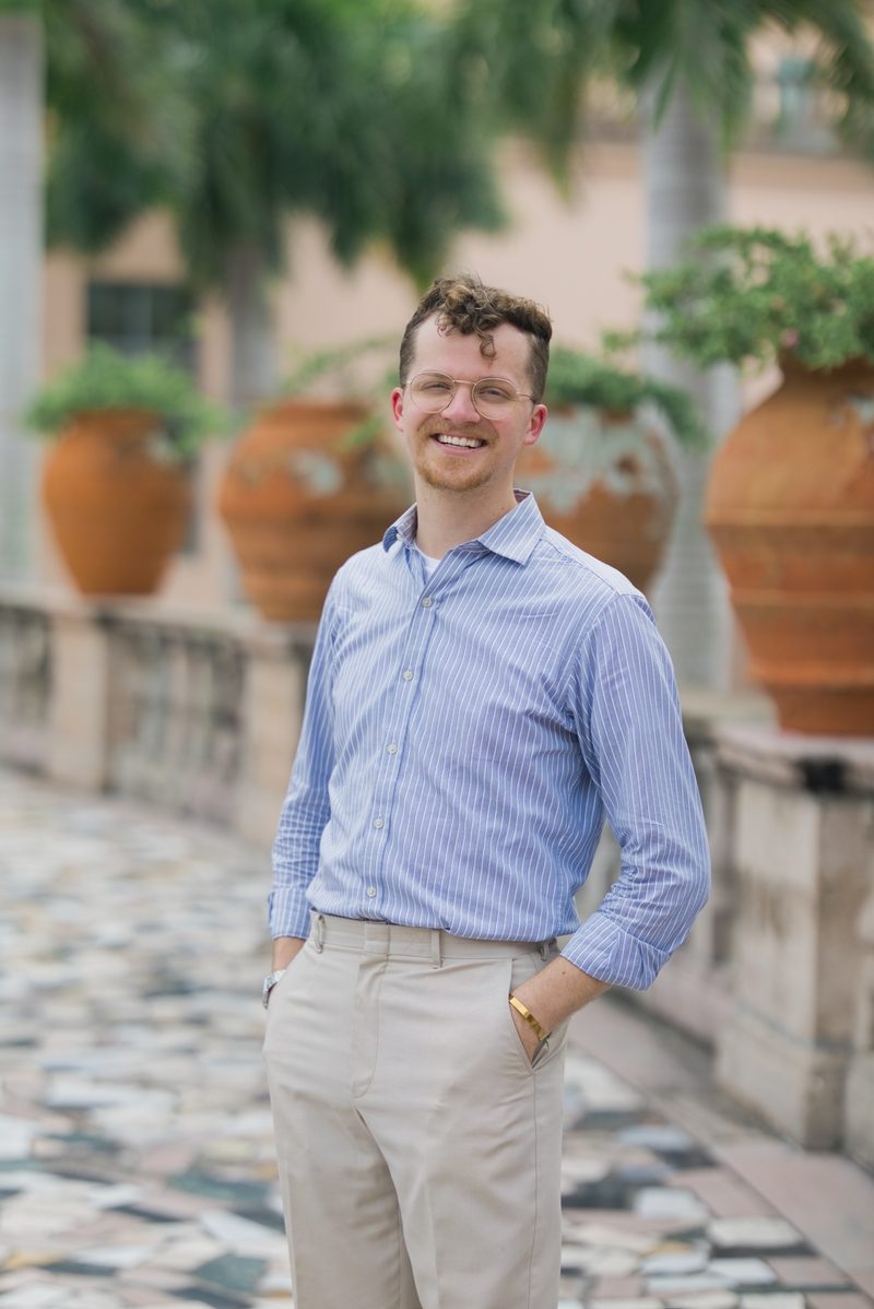 Grant smiles with his hands in his pockets on a mosaic terrace lined with terracotta urns
