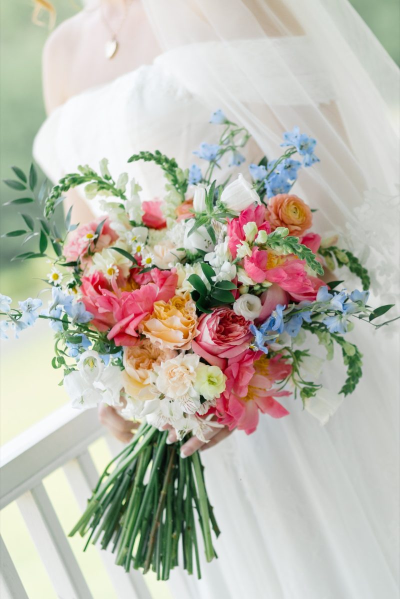 Bride's bouquet of coral peonies and blue delphinium