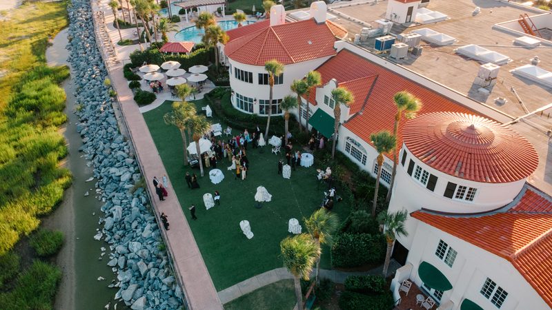 Aerial view of a seaside resort courtyard set for a wedding reception at golden hour