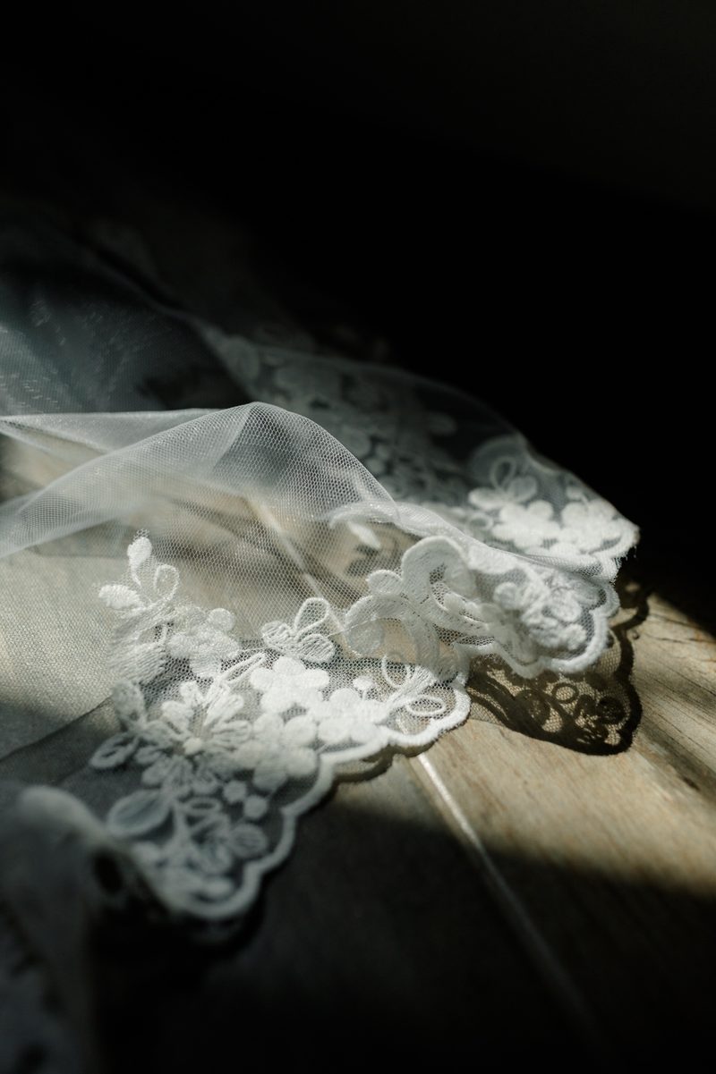 Lace edge of a wedding veil lit by a shaft of window light