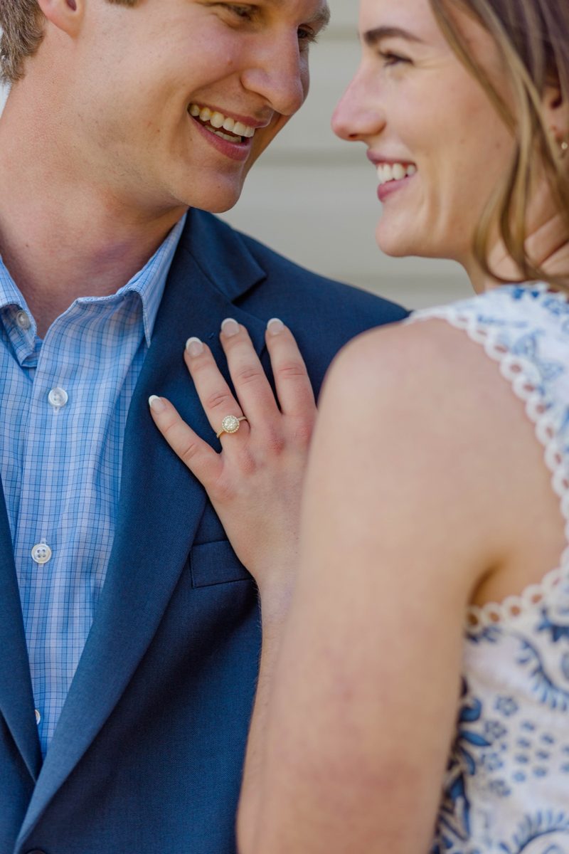 Close-up of the couple laughing together, her ring hand on his lapel