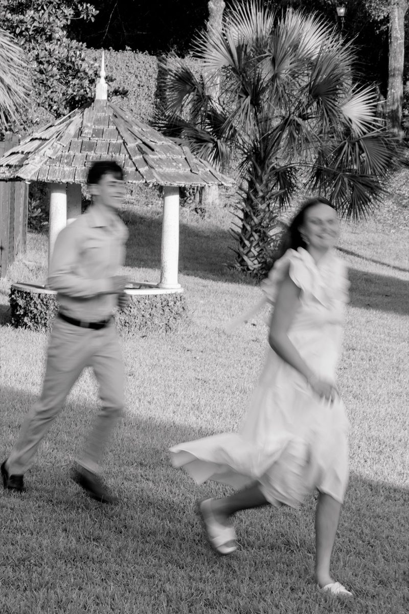Black-and-white: couple run past a garden gazebo