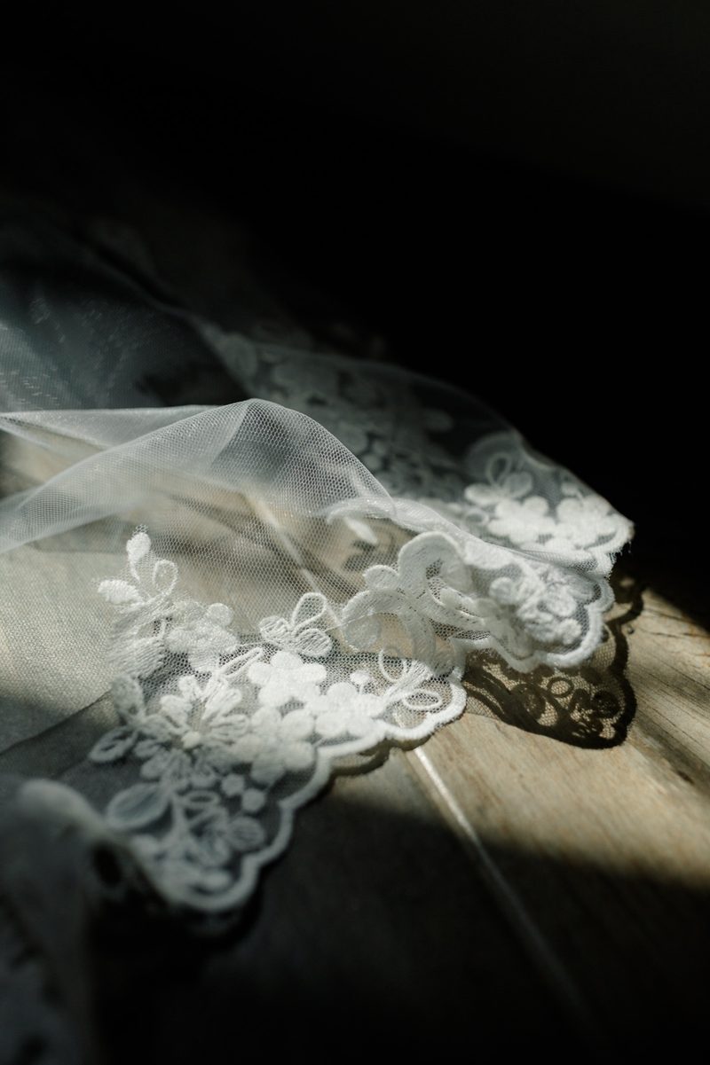 Lace veil edge lit by a single beam of light against a dark background