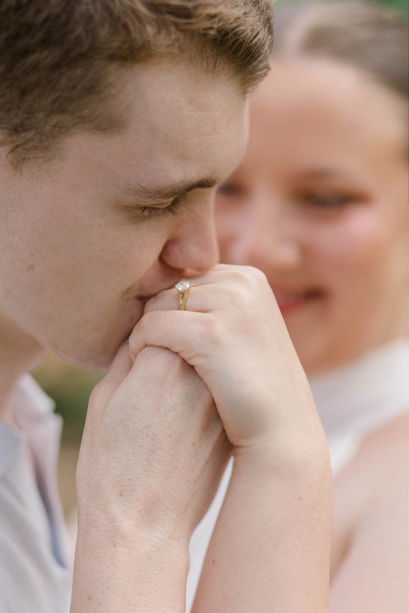 Fiancé kisses her hand, his ring hand held close to his face