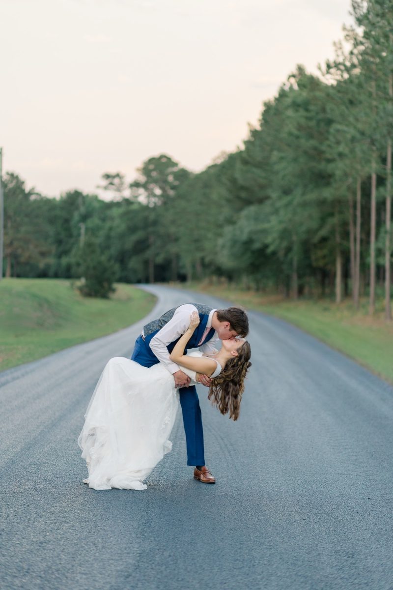 Groom dips the bride on a quiet road at dusk
